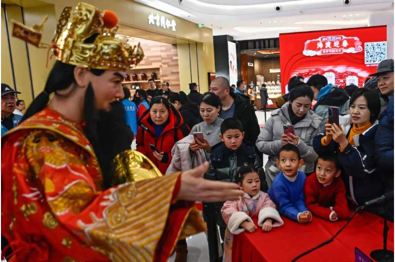 Un robot humanoïde en costume traditionnel chinois répond aux questions dans une foire du temple sur le thème de l'IA à Pékin